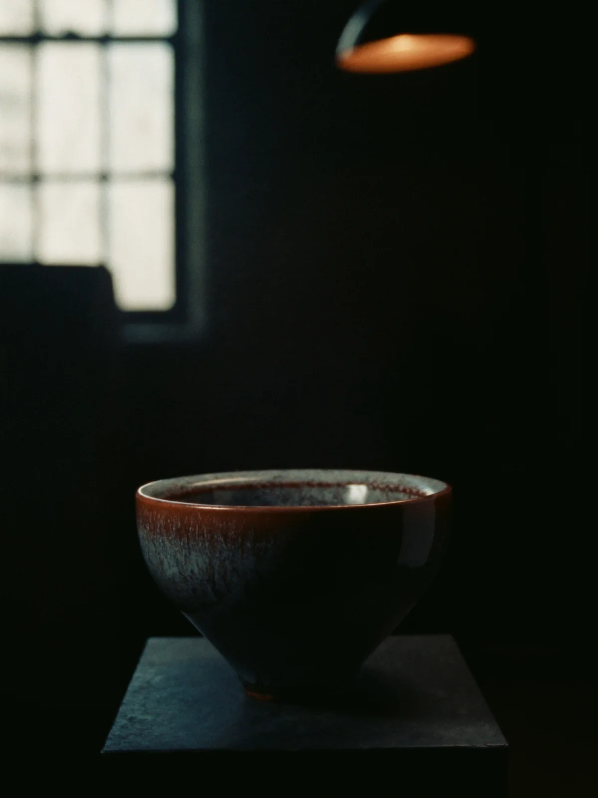 A deep stoneware serving bowl with a glossy dark iron glaze and a rust rim.