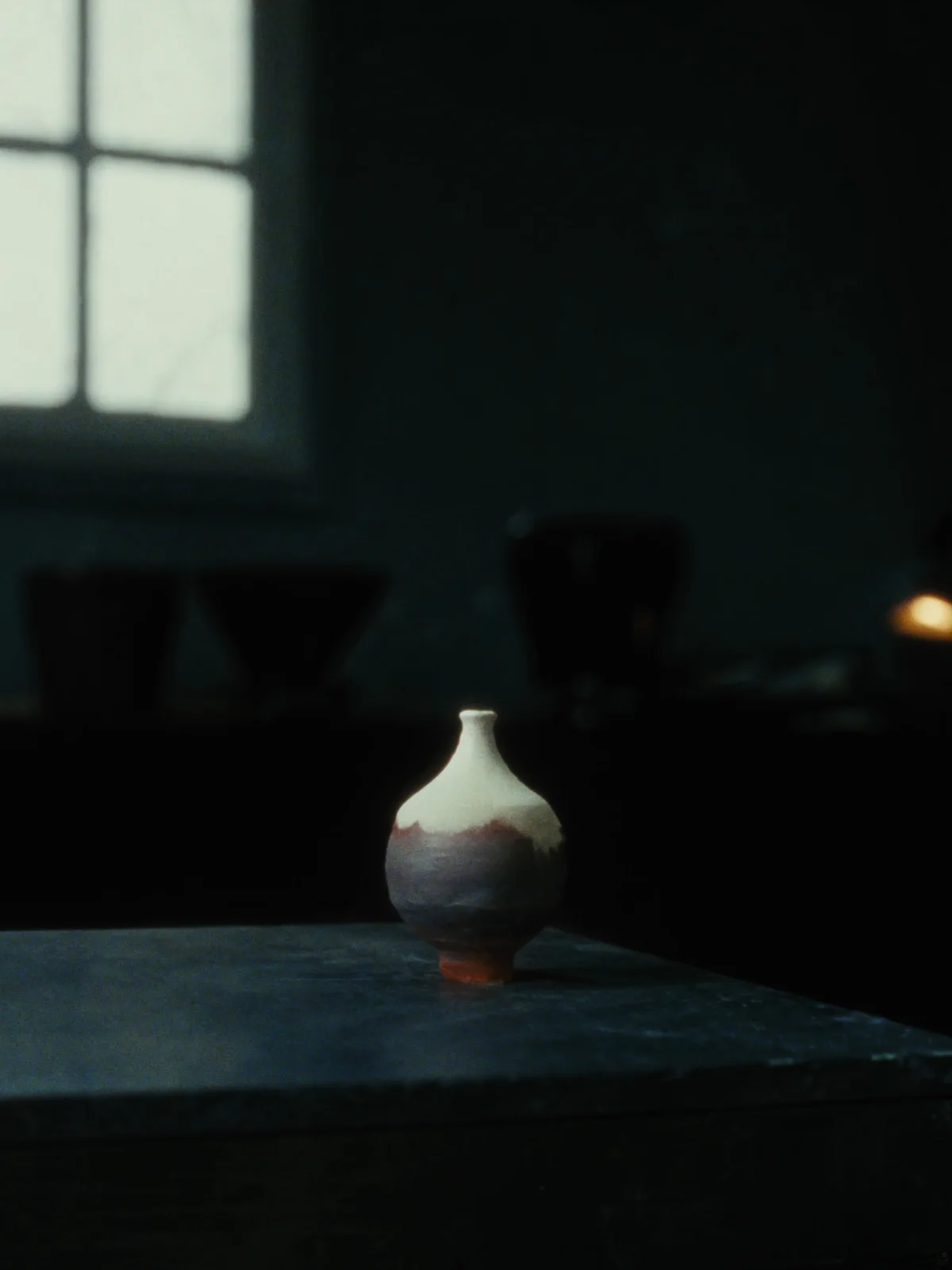 A small bottle-form bud vase in matte bone-white glaze over dark clay.