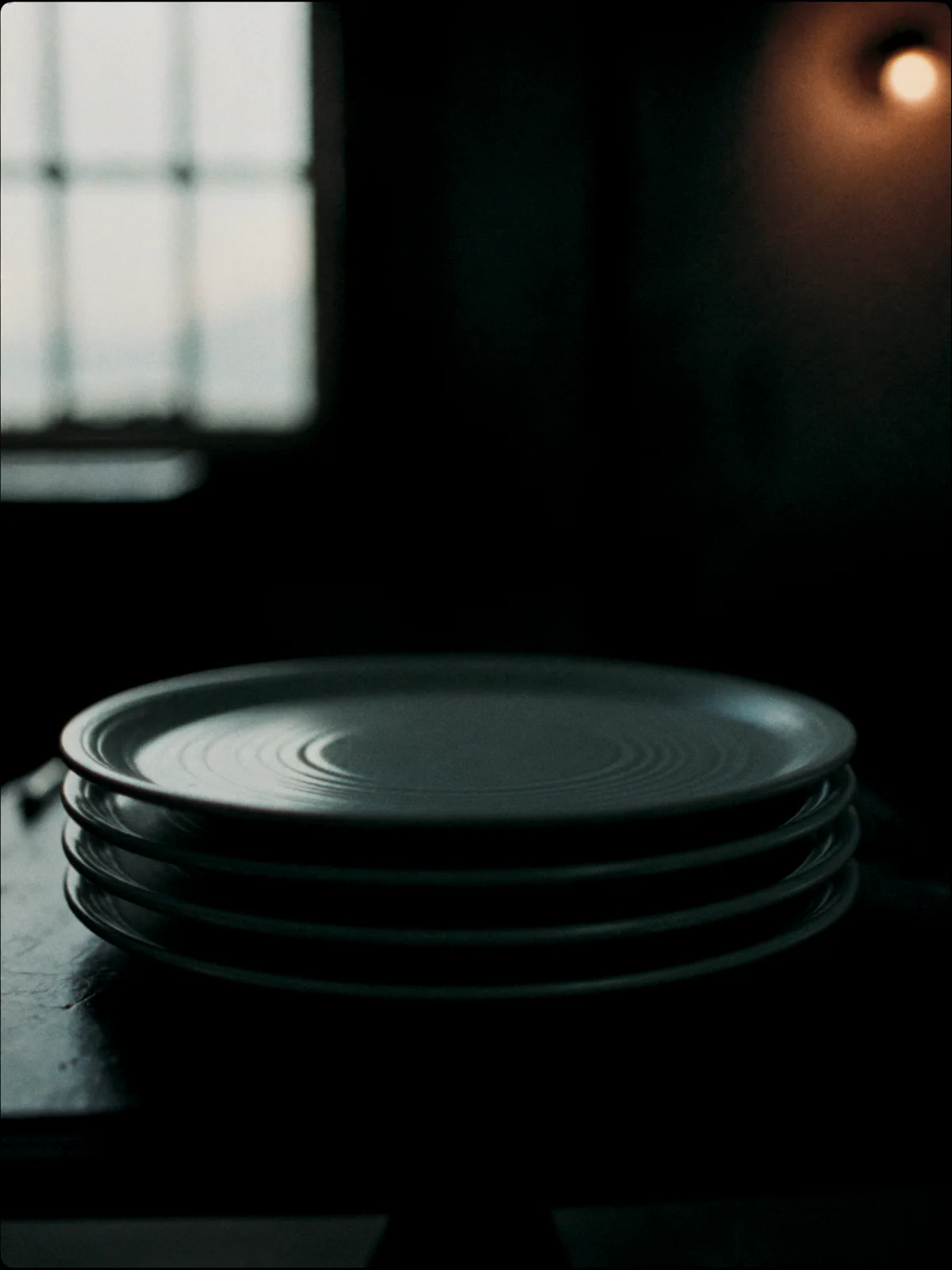 A stack of four stoneware dinner plates in a satin ash-grey glaze.